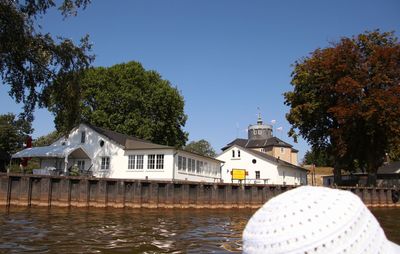 Buildings by river against clear sky