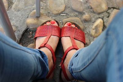 Low section of woman wearing red sandal on footpath