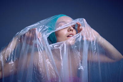 Portrait of beautiful young woman against blue background