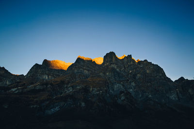Low angle view of rocks against clear blue sky