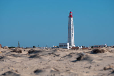 Lighthouse on beach against clear sky