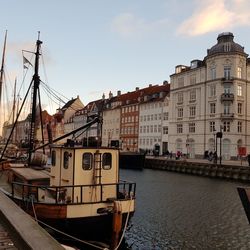 Sailboats moored in sea against buildings in city