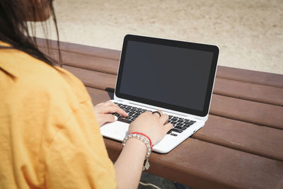 Midsection of woman using mobile phone while sitting on table