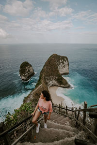 Rear view of woman sitting on sea against sky