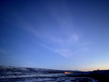 Scenic view of snowcapped mountains against blue sky at night