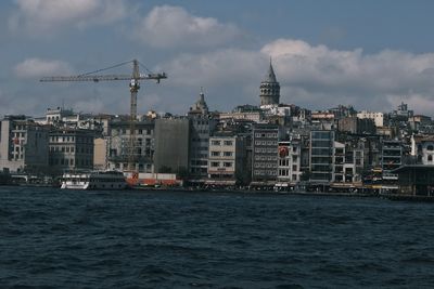 Sea by buildings against sky in city