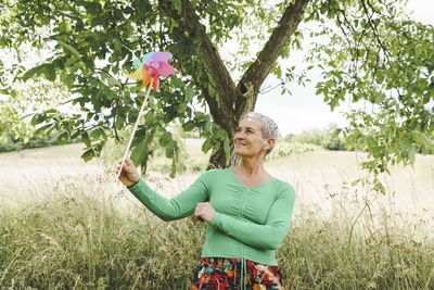 Portrait of young woman with arms raised standing on field