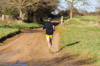 Rear view of man running on footpath