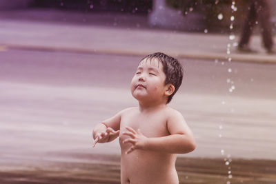 Full length of shirtless boy looking at water