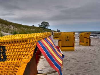 Hooded chairs on beach against sky