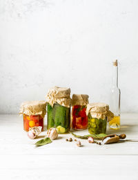 Various fruits in jar on table against white background