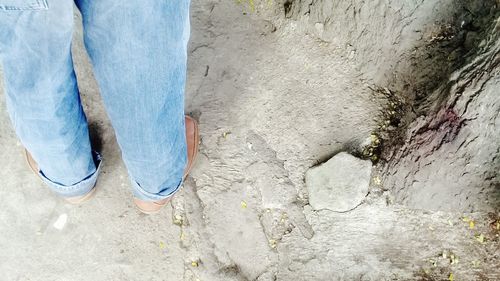 Low section of man standing on footpath by wall