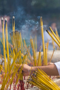 Cropped hand holding yellow incenses