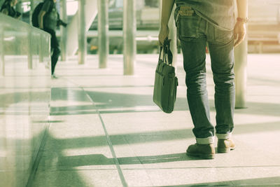 Low section of man walking on tiled floor