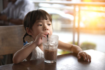 Portrait of boy drinking water from glass on table