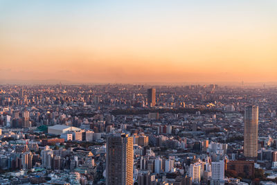 Aerial view of buildings in city against sky during sunset