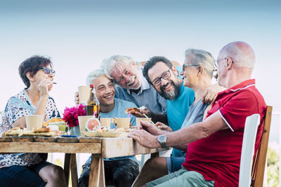 Cheerful family sitting outdoors against sky