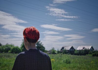 Rear view of man standing on field against sky