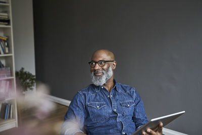 Mature man holding tablet, smiling