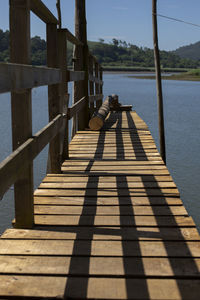 Shadow of pier on lake against sky