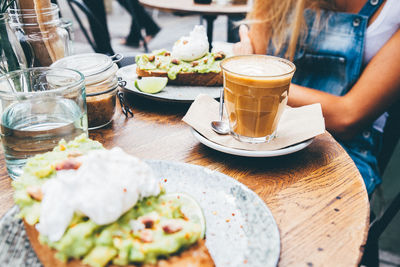 Midsection of woman having food and coffee at sidewalk cafe