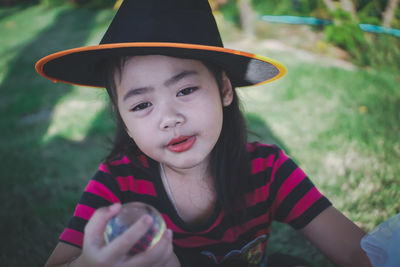 Portrait of girl wearing witch hat holding crystal ball