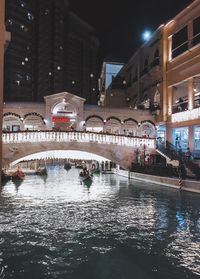 Bridge over canal amidst buildings in city at night