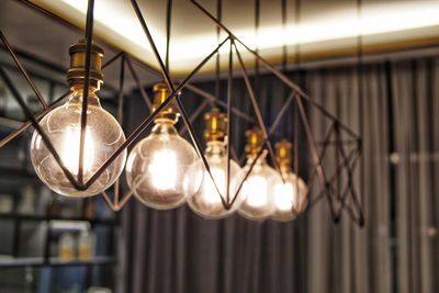 Low angle view of illuminated light bulb hanging on ceiling