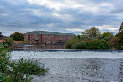 Buildings by river against sky