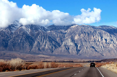 Road leading towards mountains against sky