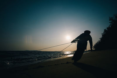 Silhouette man on beach against sky during sunset