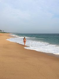 Woman walking at beach against sky