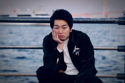 Portrait of young man looking away against sea