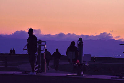 Silhouette people standing against sky during sunset