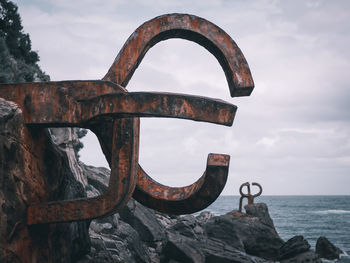 Close-up of rusty metal by sea against sky