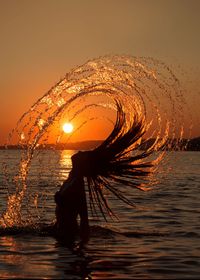 Silhouette woman by sea against sky during sunset