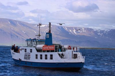 Nautical vessel on sea by snowcapped mountains against sky