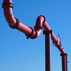 Low angle view of pipeline against clear blue sky