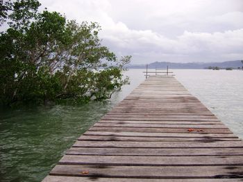 Wooden pier over lake against sky