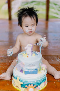 Close-up of cute girl playing with cake on the floor