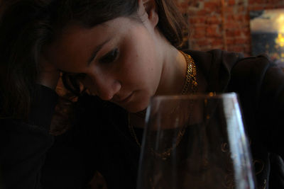 Close-up woman sitting by wineglass at home