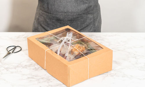 Midsection of woman holding gift box on table