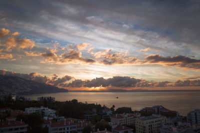 High angle view of town by sea against sky during sunset