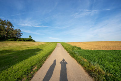 Road amidst field against sky