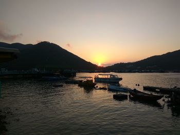 Boats sailing on sea against clear sky during sunset