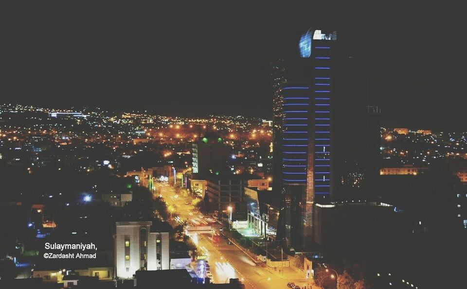 illuminated, night, city, building exterior, architecture, cityscape, built structure, high angle view, city life, transportation, street, road, traffic, car, city street, lighting equipment, land vehicle, sky, dark, street light