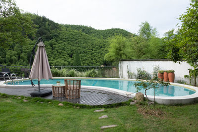 Scenic view of swimming pool by trees against sky