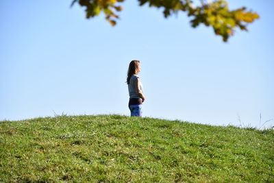 Woman standing on field against clear sky