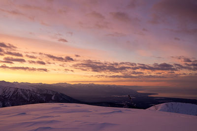 Scenic view of snow covered mountains against sky at sunset