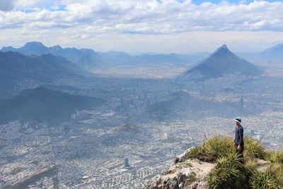 Rear view of man standing on mountain against sky